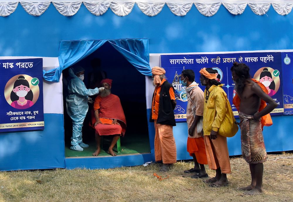 A healthcare worker wearing personal protective equipment (PPE) collects a swab sample from a Sadhu or a Hindu holy man for a rapid antigen test in Kolkata, India, January 8, 2021. u00e2u20acu201d Reuters picnn