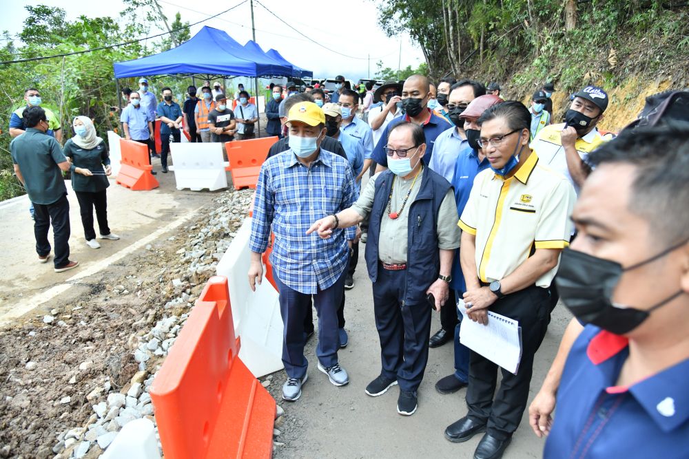 Sabah Chief Minister Datuk Seri Hajiji Noor (left) observes repair work on a damaged stretch of road between Penampang and Tambunan January 26, 2021. u00e2u20acu201d Picture by Julia Chan