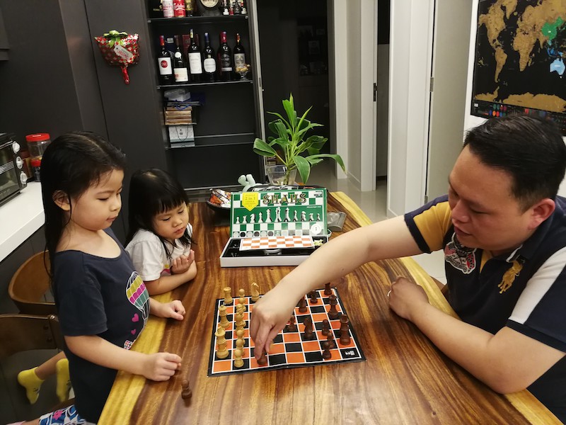 Ng (right) guiding his daughters on the basic strategies of chess. u00e2u20acu201d Picture courtesy of Ng Hong Haw