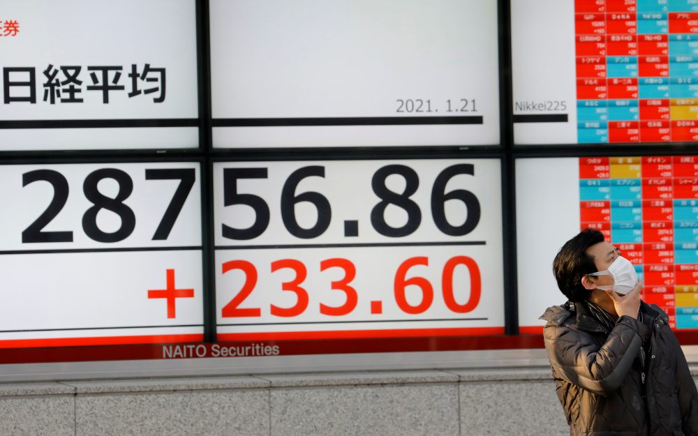 A man wearing a protective mask, amid the coronavirus disease outbreak, stands in front of an electric board showing Nikkei index outside a brokerage in Tokyo, Japan January 21, 2021. u00e2u20acu201d Reuters pic