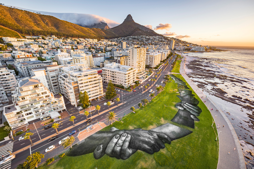 An aerial view shows a giant land-art fresco by French artist Saype, painted for the 9th step of his worldwide u00e2u20acu02dcBeyond Wallsu00e2u20acu2122 project in Sea Point, Cape Town, South Africa January 19, 2021. u00e2u20acu201d Valentin Flauraud for Saype handout pic via Reutersnn