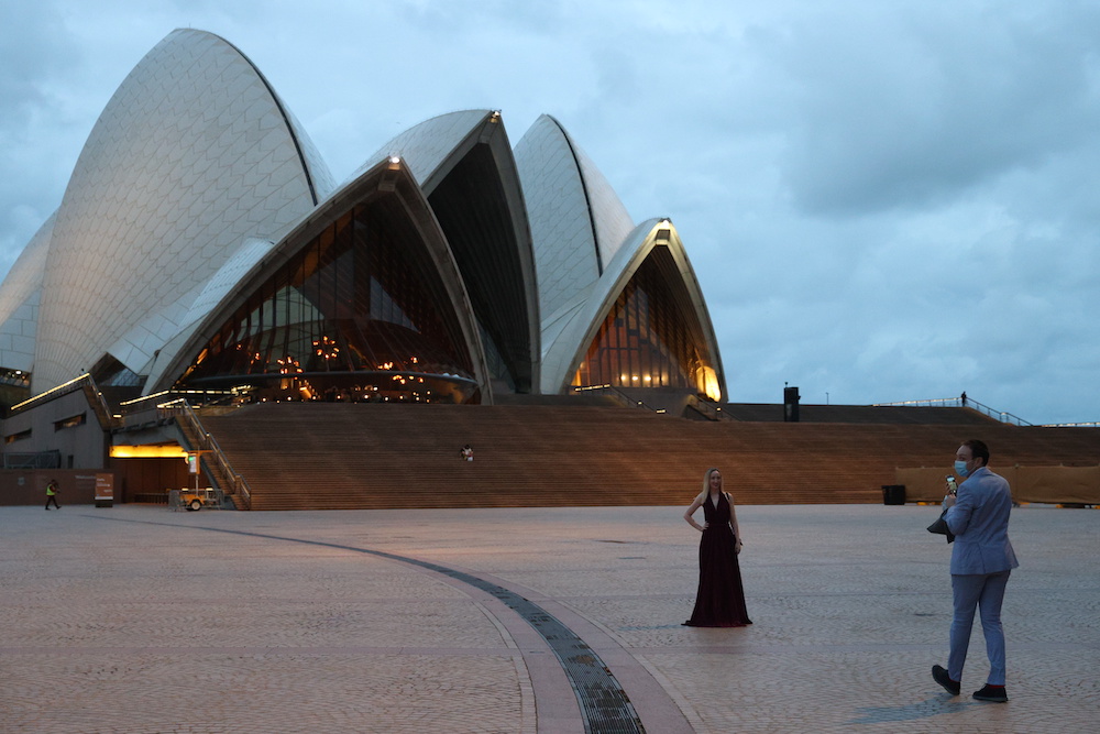 A woman poses for a photo in front of the Sydney Opera House as a small number of people begin celebrating New Year's Eve at the Sydney Harbour waterfront amidst tightened Covid-19 prevention regulations in Sydney, Australia, December 31, 2020. u00e2u20acu2022 Reuter