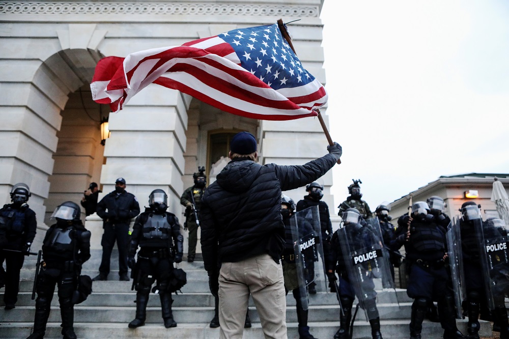A supporter of US President Donald Trump holds a US flag while confronting law enforcement officers at the US Capitol in Washington January 6, 2021. u00e2u20acu2022 Reuters pic