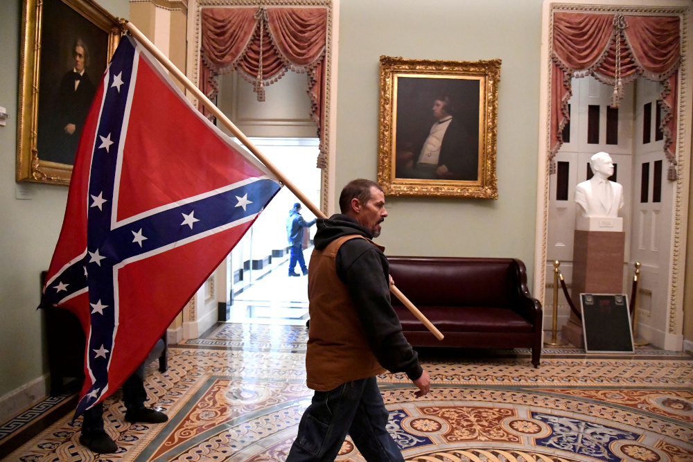 A supporter of President Donald Trump carries a Confederate battle flag on the second floor of the US Capitol near the entrance to the Senate after breaching security defences, in Washington, US, January 6, 2021. — Reuters pic