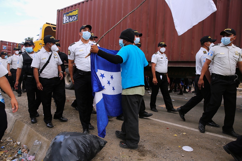 A Honduran migrant holds his country's flag as Guatemalan security forces clear a road where the migrants have been camping after authorities halted their trek to the United States, in Vado Hondo, Guatemala January 18, 2021. u00e2u20acu2022 Reuters pic