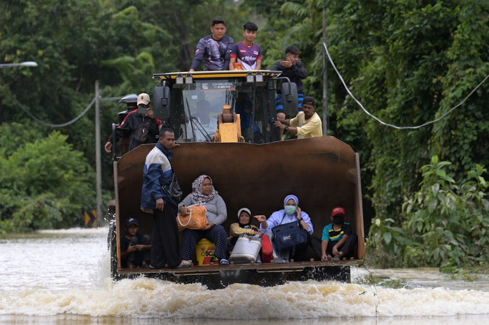 Residents ride a digger vehicle through floodwaters following heavy monsoon downpour in Lanchang, Pahang January 6, 2021. u00e2u20acu201d AFP pic