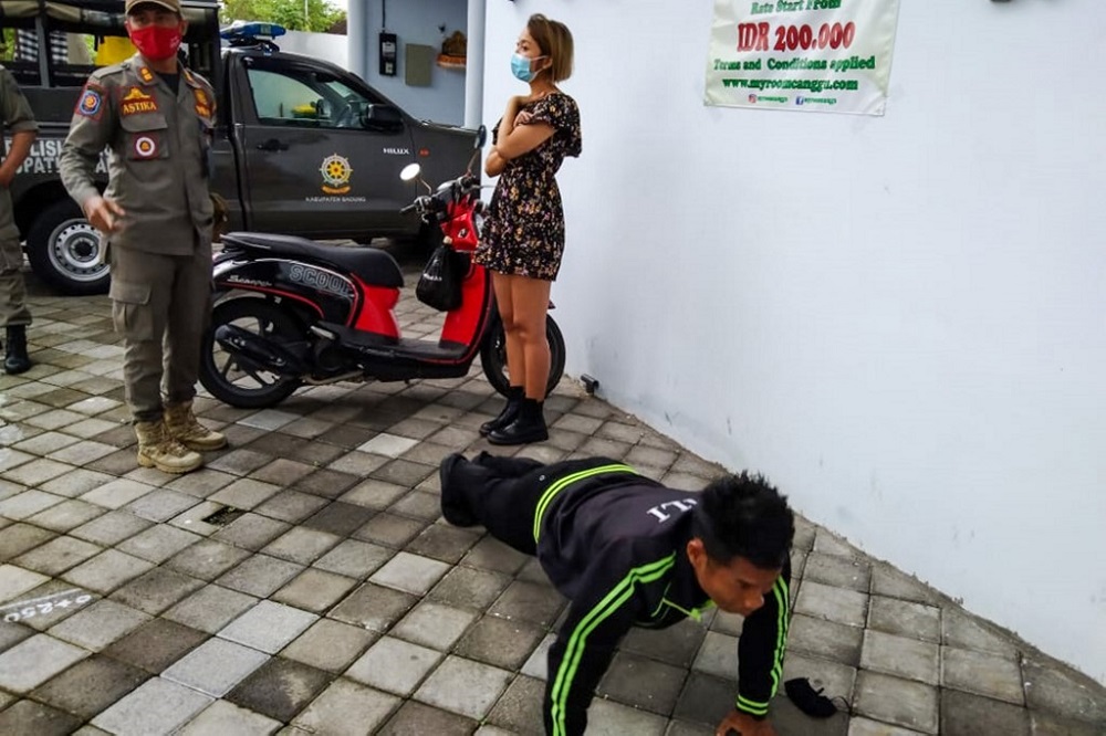 A man performs push-ups as punishment for not wearing or improperly wearing face masks amid the Covid-19 coronavirus pandemic, along a street in Badung, Indonesia's resort island of Bali. u00e2u20acu2022 AFP pic