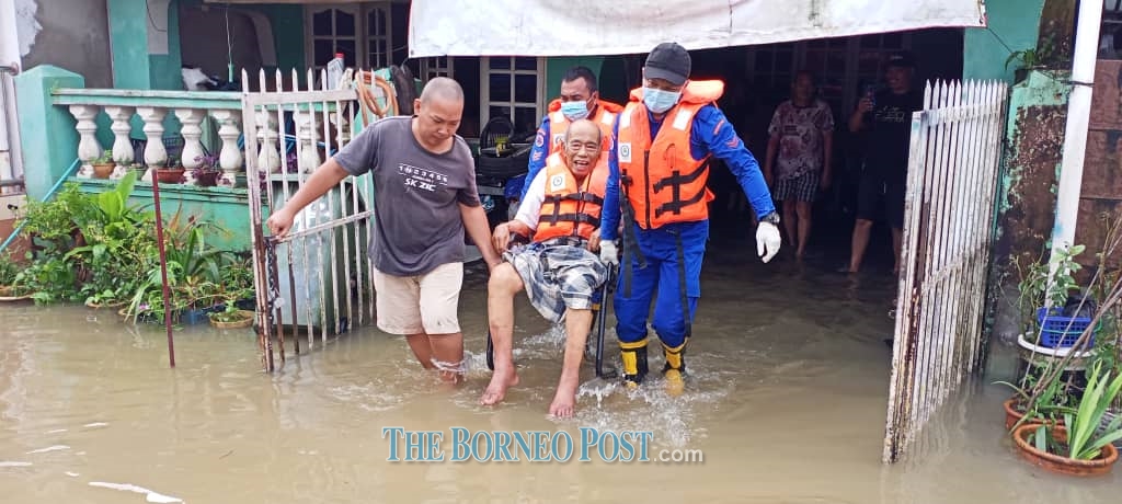Members from the Civil Defence Force evacuating a flood victim at Taman Malihah this morning. u00e2u20acu2022 Borneo Post pic