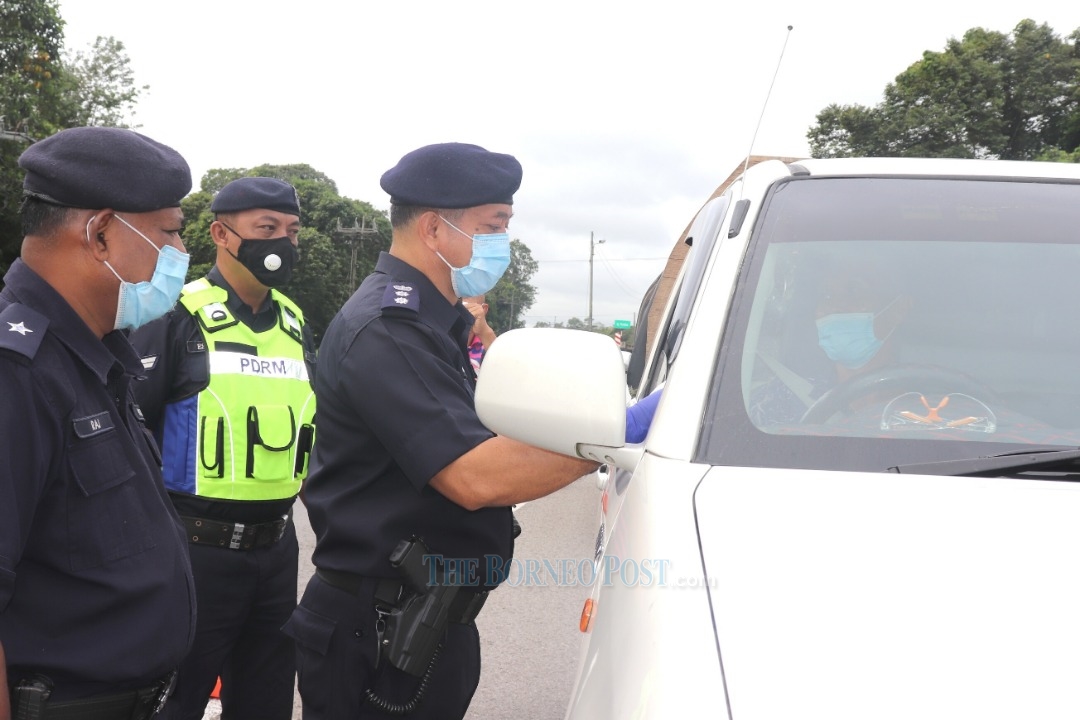 Stanley (second left) checking the details of a driver at the CMCO roadblock near the Paradom roundabout in Sibu. u00e2u20acu2022 Borneo Post pic