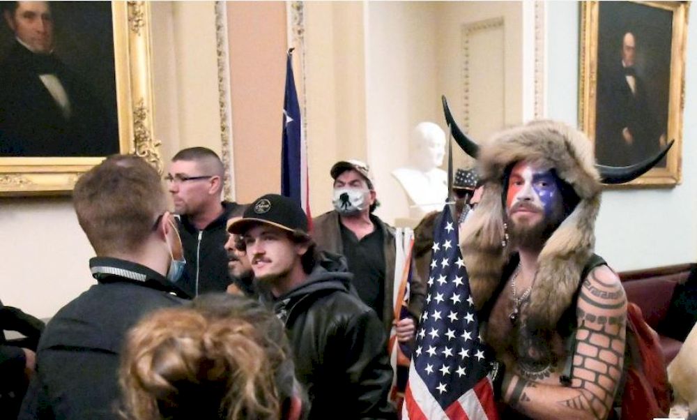 Jacob Anthony Chansley, also known as Jake Angeli, of Arizona, stands with other supporters of US President Donald Trump as they demonstrate on the second floor of the US Capitol near the entrance to the Senate after breaching security defences, in Washin