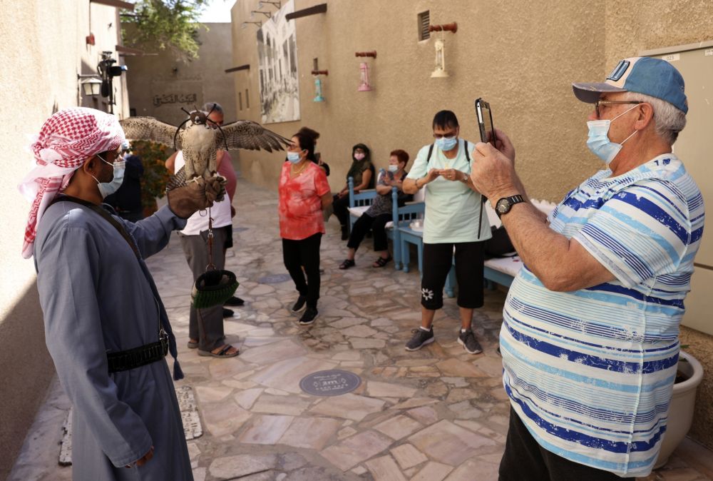A mask-clad Israeli tourist photographs a falconer holding a falcon during a visit to the historic al-Fahidi neighbourhood of Dubai. u00e2u20acu201d AFP pic