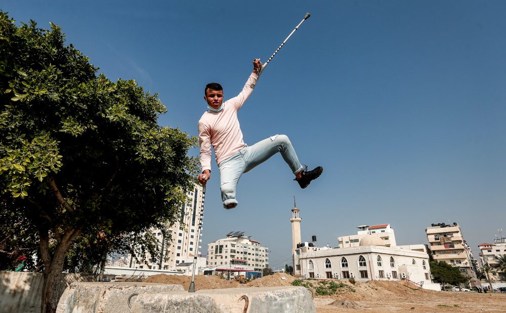 Mohamed Aliwa, a Palestinian youth whose leg was amputated near the knee in 2018 after he was hit by Israeli army fire during protests, shows off his parkour skills despite his disability and while on crutches in Gaza City January 4, 2021. — AFP pic