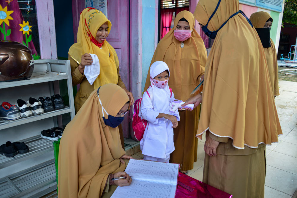 Teachers check the body temperature of a pupil as a precautionary measure against the Covid-19 coronavirus at a kindergarten in Banda Aceh January 5, 2021. u00e2u20acu201d AFP picnn