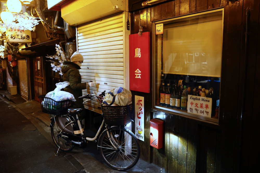 A staff of a Japanese izakaya restaurant shutters her shop after the 8pm closure for eateries at a pub alley in the Shinjuku area of Tokyo January 8, 2021, during the first day under a state of emergency over the coronavirus pandemic. u00e2u20acu201d AFP pic 