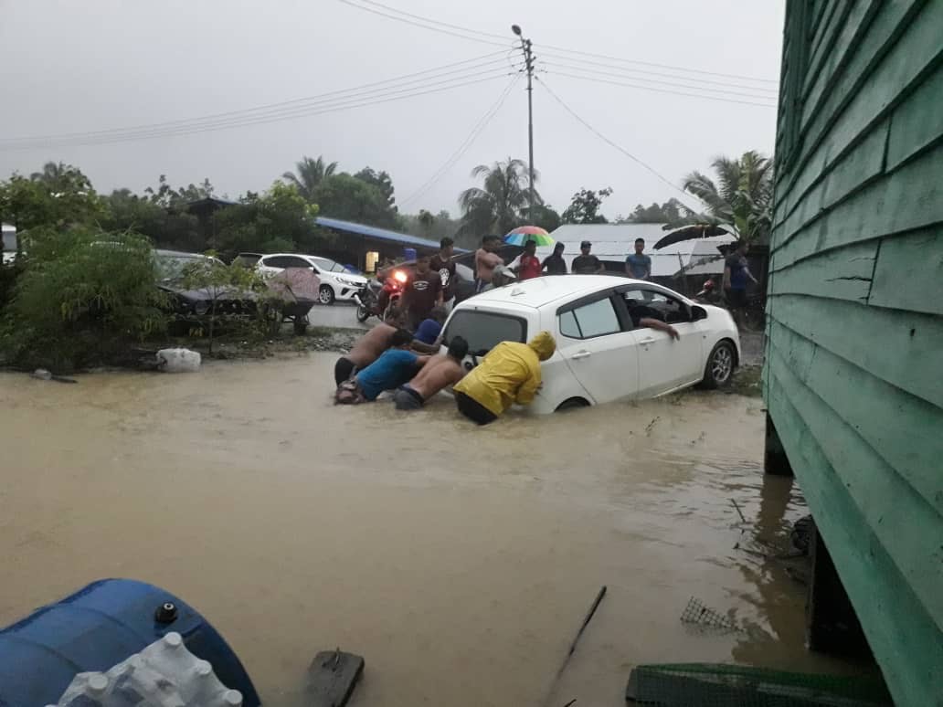 Villagers in Kampung Liu push a car to higher ground as floodwaters continued to rise. u00e2u20acu201d Borneo Post pic