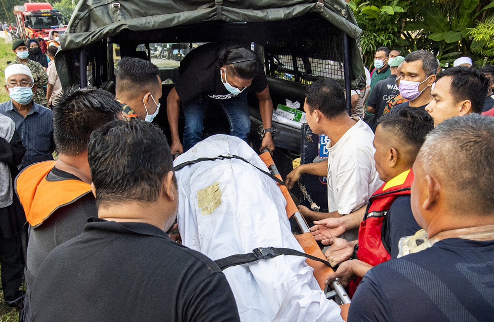 Fire and Rescue Department personnel and Kota Baru police carry the body of Wan Muhammad Azamudin Wan Azlan, 16, who drowned in Sungai Perupok in Kampung Tikat, January, 19, 2021. u00e2u20acu201d Bernama picnn