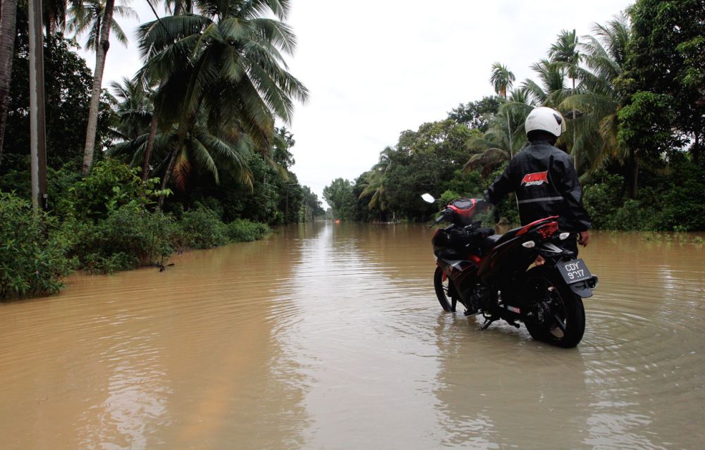 A motorcyclist surveys the submerged road connecting Kampung Cherok Paloh with Kampung Ubai in Kuantan January 13, 2021. u00e2u20acu201d Bernama pic