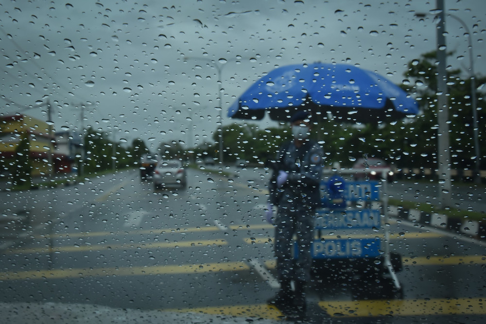 Despite the rain, policemen remain on duty at Jalan Patau-Patau in Labuan, January 17, 2021. u00e2u20acu201d Bernama pic 