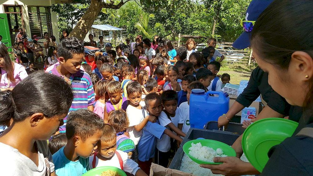 Children from a village in Davao, the Philippines, are seen in 2012 waiting to collect food bought with the proceeds from Olive Vine restaurant. — Photo courtesy of Jason Ong
