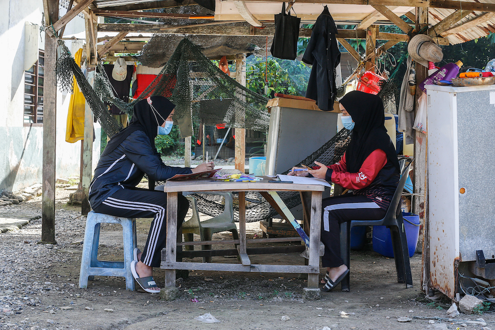 Nur Alea Soffiyyah Ahmad Hanif (left) and her schoolmate Hanis Syuhada Razali (right) attend online classes in front of their house on Pulau Aman January 22, 2021. — Picture by Sayuti Zainudin