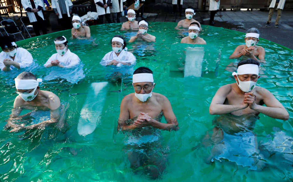 Participants wearing protective face masks pray as they take an ice-cold bath during a ceremony to purify their souls and to wish for overcoming the pandemic at the Teppozu Inari shrine in Tokyo, January 10, 2021. u00e2u20acu201d Reuters pic
