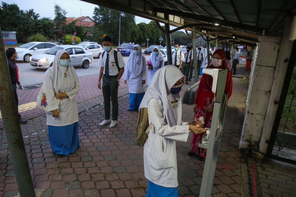 A student sanitises her hands after having her temperature recorded at Sekolah Menengah Kebangsaan Bukit Jelutong in Shah Alam January 20, 2021. u00e2u20acu201d Picture by Yusof Mat Isa