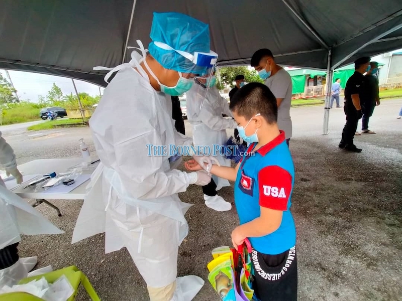 A health worker fixing a white wristband on one of the individuals who had underwent swab test today. u00e2u20acu201d Borneo Post Online pic