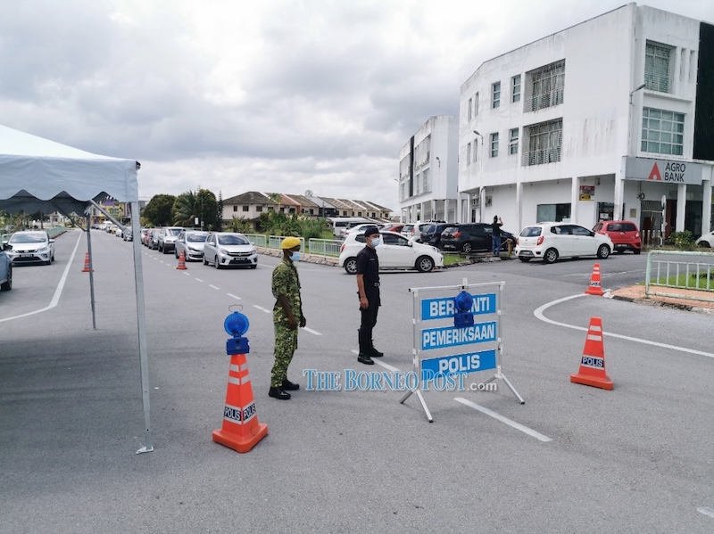 One of the roadblocks set up at Jalan Univista, with more than 30 vehicles are seen queueing up at the drive-through swab test area earlier today. u00e2u20acu201d Picture by Roystein Emmor via Borneo Post Online