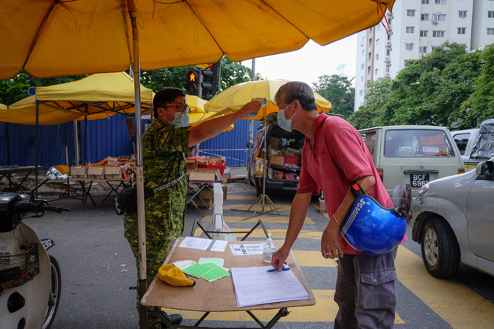 A Peopleu00e2u20acu2122s Volunteer Corps (Rela) member checks the temperature of people at the entrance of the Taman Desa Phase 1 night market in Kuala Lumpur February 5, 2021. u00e2u20acu201d Picture by Yusof Mat Isa