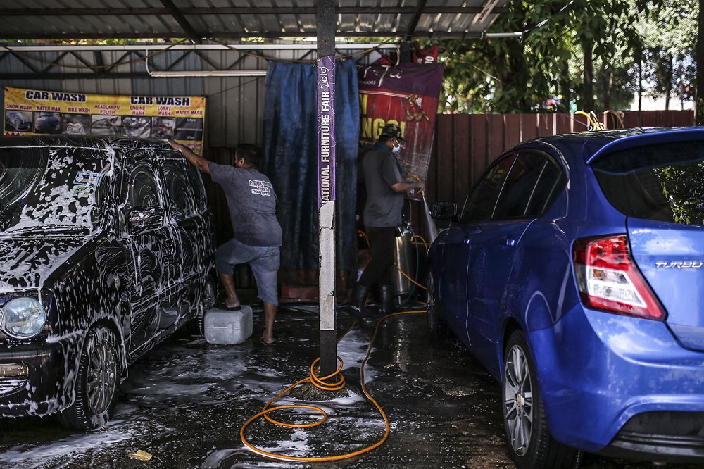 Staff at a car wash centre are seen hard at work in Kuala Lumpur February 6, 2021. u00e2u20acu201d Picture by Hari Anggara