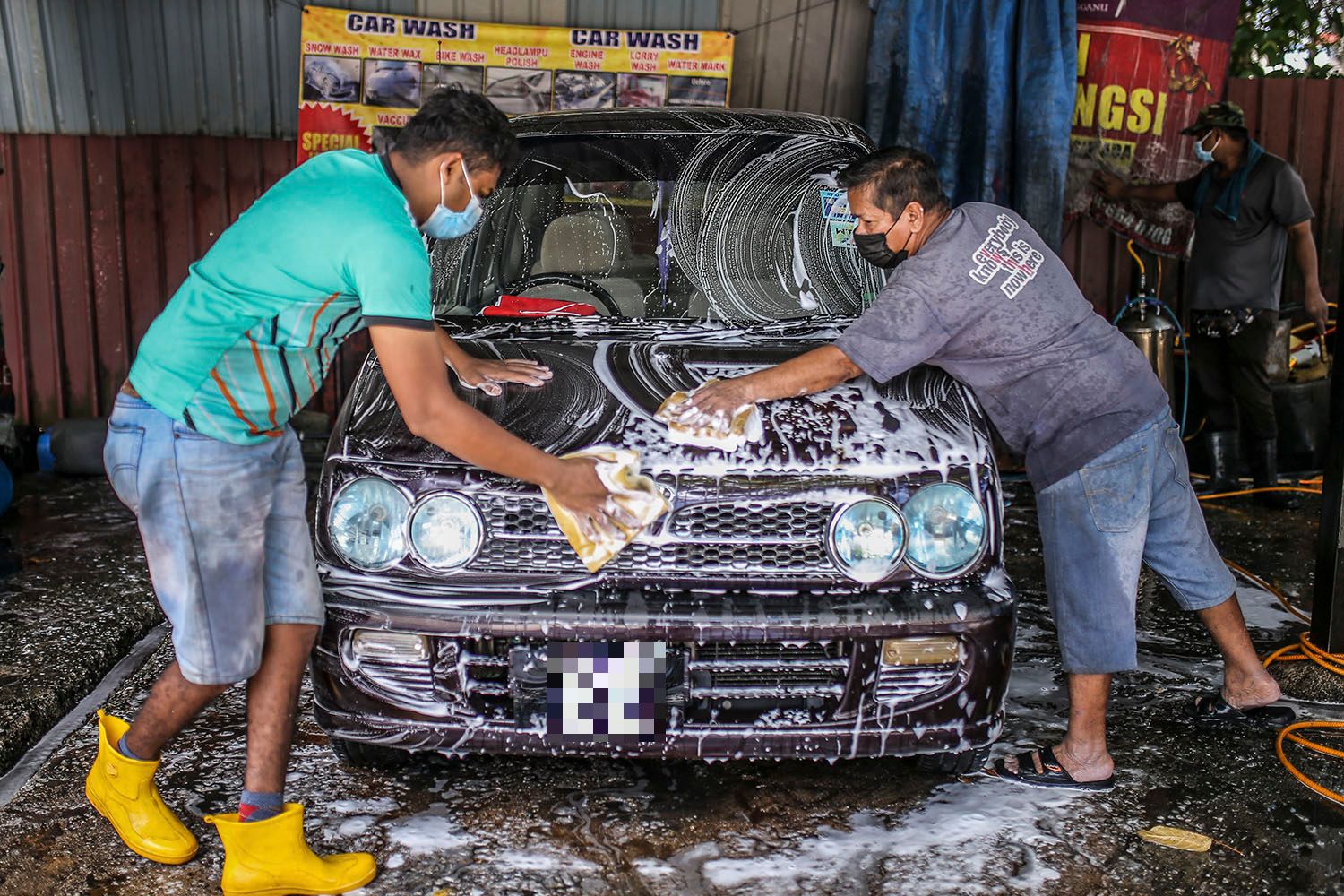 Staff at a car wash centre are seen hard at work in Kuala Lumpur February 6, 2021. u00e2u20acu201d Picture by Hari Anggara