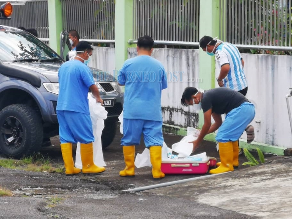 Healthcare workers donning their personal protective equipment before entering the care centre where the man was found dead. u00e2u20acu201d Borneo Post pic