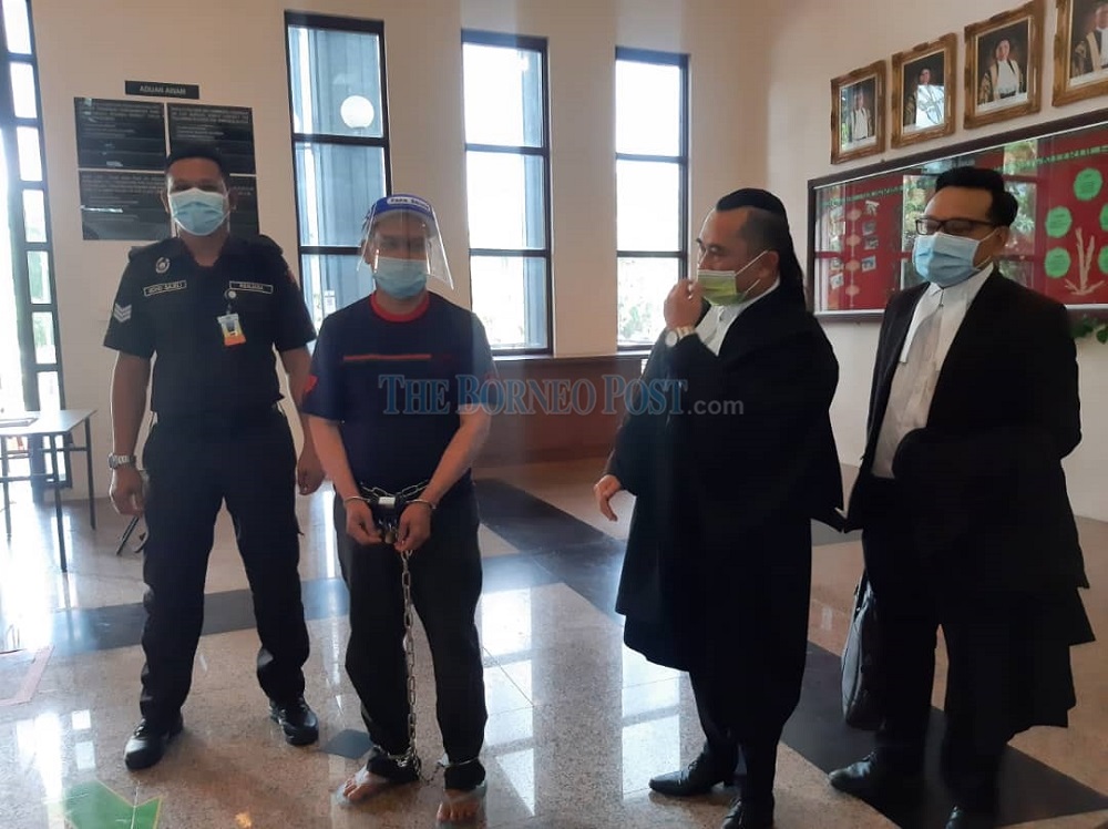 Bawa (second left) being escorted by a policeman talking to defence counsels Abdul Rahman (second right) and Christopher (right). u00e2u20acu201d Borneo Post Online pic