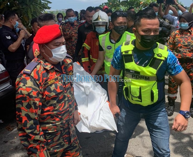 The body of an unidentified woman is being transferred to a police vehicle. u00e2u20acu201d Borneo Post Online pic