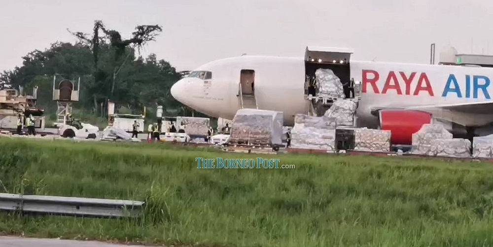 Personnel seen unloading the vaccine from the plane on the tarmac. — Picture by Chimon Upon via Borneo Post Online