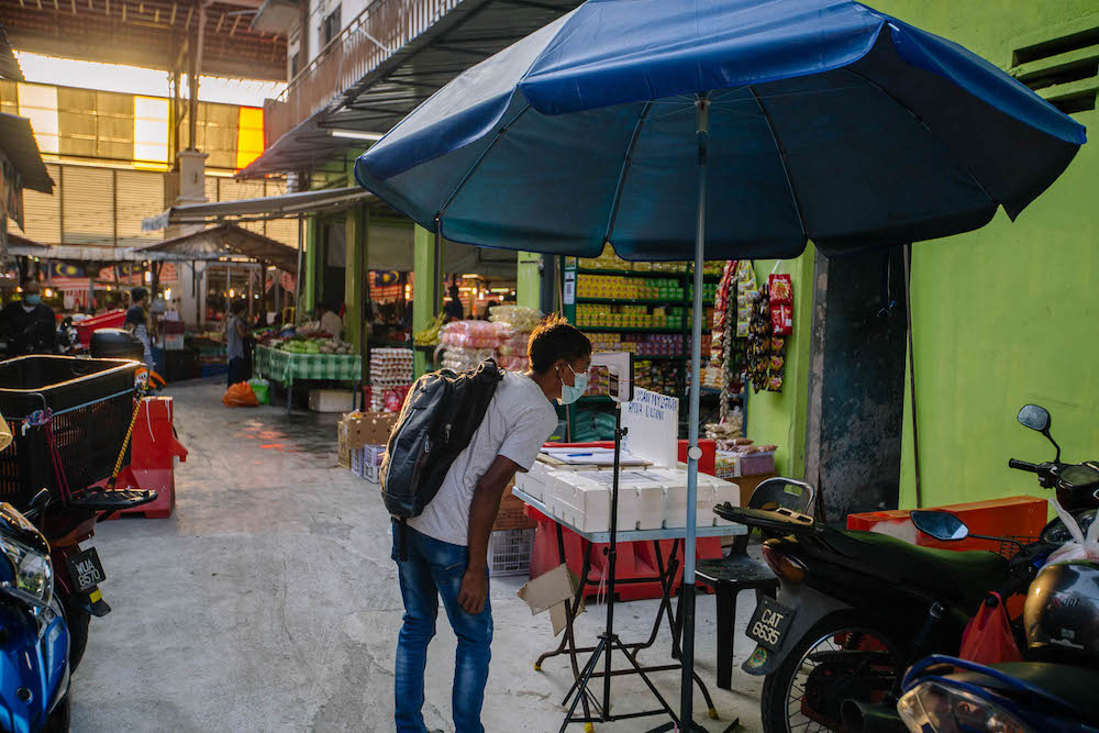 A man wearing a face mask scans his body temperature at the entrance to the Chow Kit market in Kuala Lumpur February 28, 2021. u00e2u20acu201d Picture by Firdaus Latifu00e2u20acu00a8