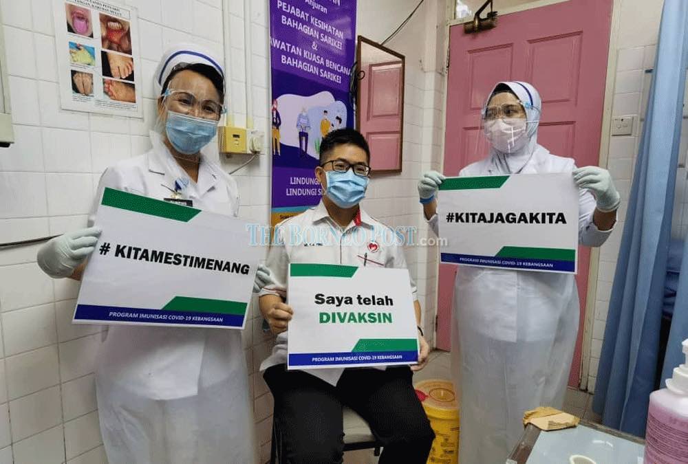 Dr Fong and nurses hold up signs promoting Covid-19 vaccination. u00e2u20acu201d Borneo Post Online pic