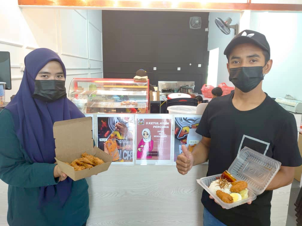 Kafe Ateyh Fried Chicken outlet owners Siti Nazirah Norzri (left) and her husband Mohammad Atif Wan Kamal showing the fried chicken and fried chicken nasi lemak meals in their shop. — Picture by Ben Tan