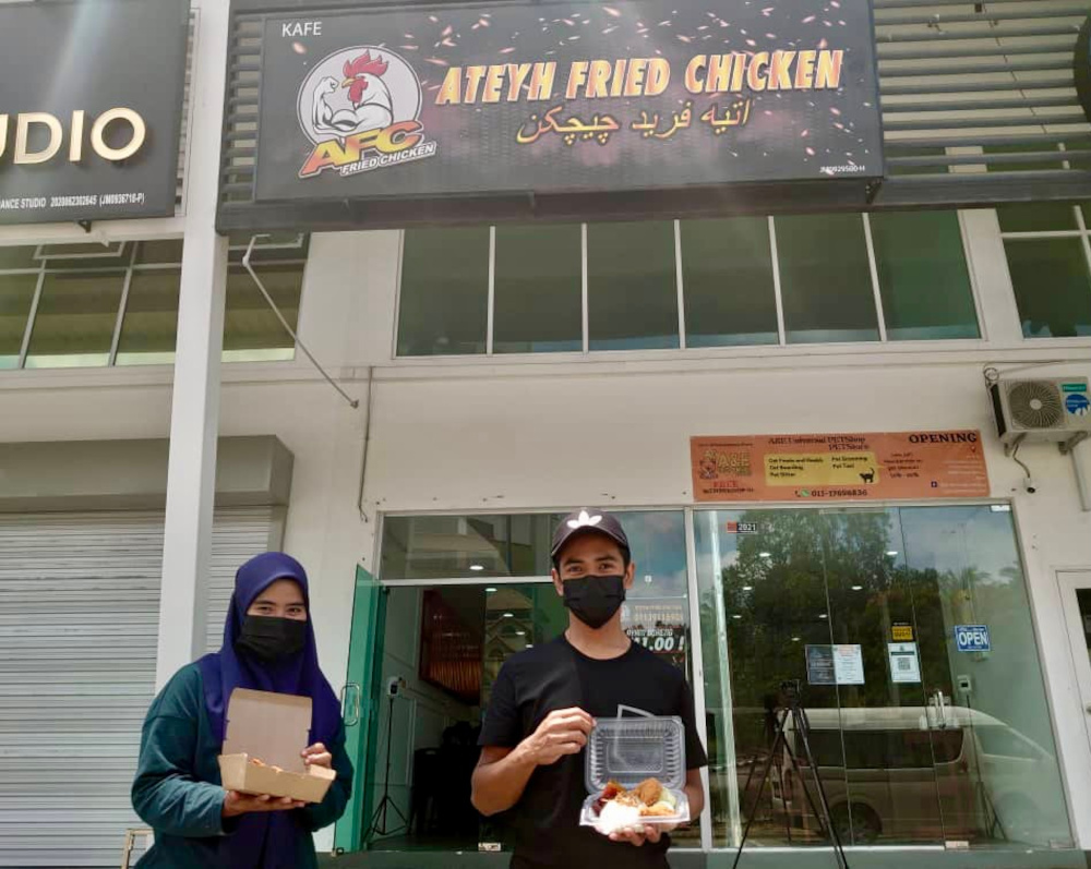 Kafe Ateyh Fried Chicken outlet owners Siti Nazirah Norzri (left) and her husband Mohammad Atif Wan Kamal started their initiative to provide free food for the needy during the second phase of the movement control order (MCO). u00e2u20acu201d Picture by Ben Tan