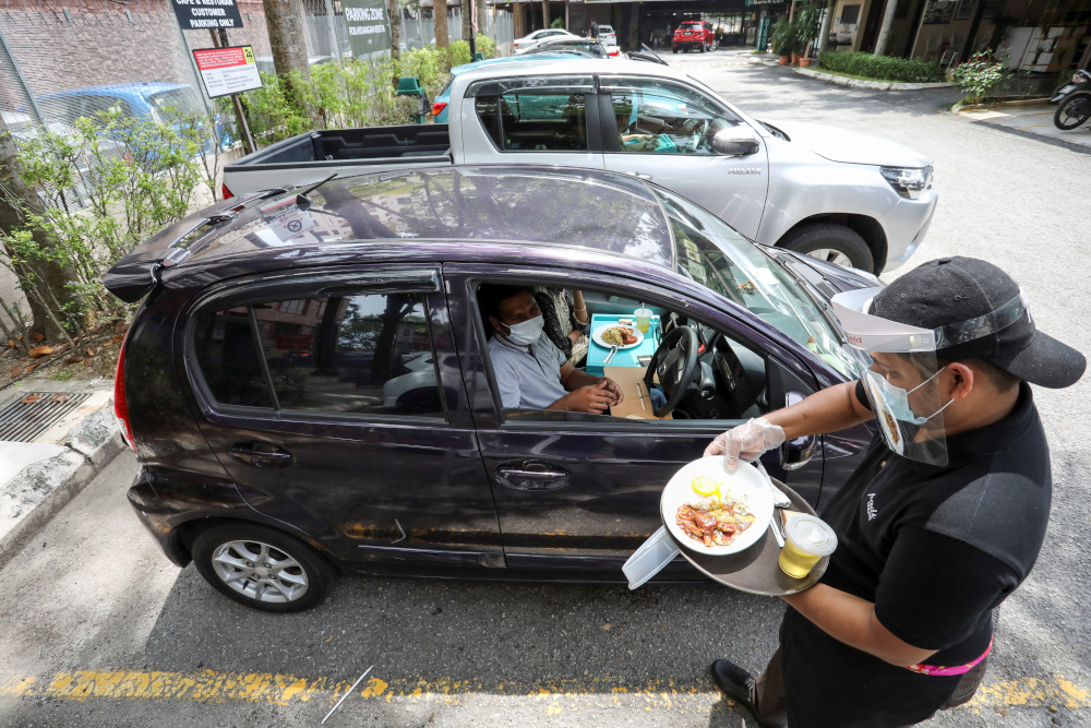A waiter serves a customer outside Padi House restaurant for u00e2u20acu02dcdine in caru00e2u20acu2122 service, during a lockdown due to the coronavirus disease outbreak, in Cyberjaya, February 4, 2021. u00e2u20acu201d Reuters pic 