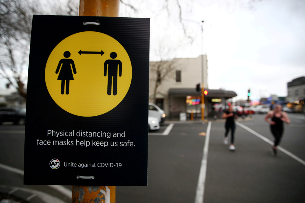 People jog past a social distancing sign on the first day of New Zealandu00e2u20acu2122s new coronavirus disease safety measure that mandates wearing of a mask on public transport, in Auckland, August 31, 2020. u00e2u20acu201d Reuters picnn