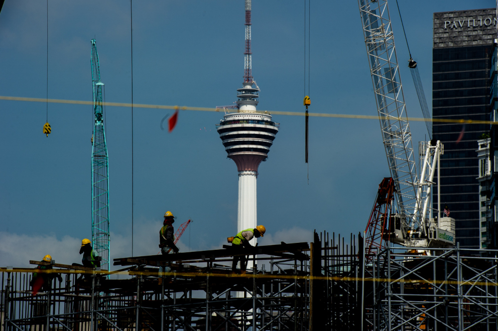 Construction workers walking across a platform at a building site in Kuala Lumpur February 14, 2021. u00e2u20acu201d Picture by Shafwan Zaidon