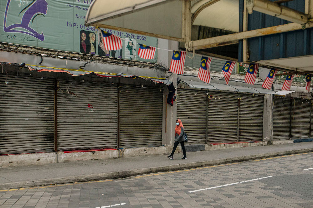 A woman wearing a face mask walks on a street, during the implementation of the movement control order (MCO 2.0) in Kuala Lumpur February 2, 2021. u00e2u20acu201d Picture by Firdaus Latif