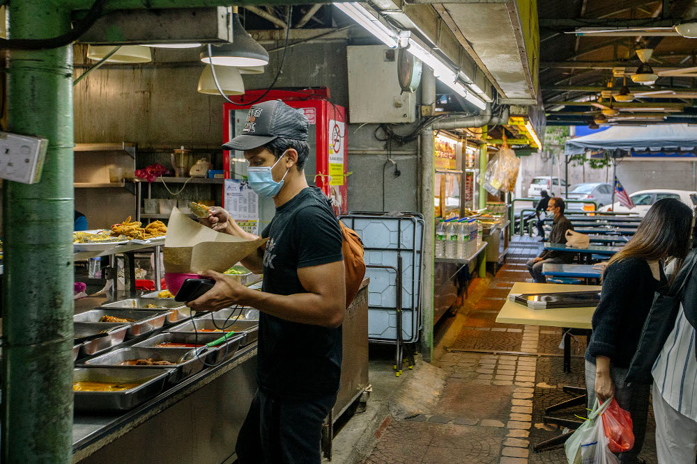 A man wearing a face mask buys food at an eatery during the implementation of the movement control order (MCO 2.0) in Kuala Lumpur February 2, 2021. u00e2u20acu201d Picture by Firdaus Latif
