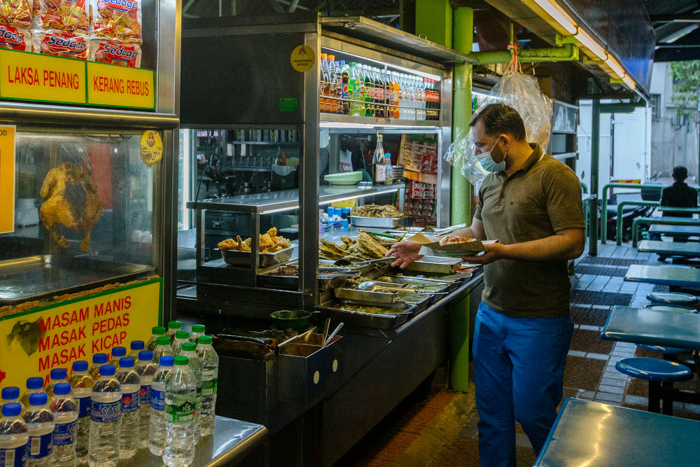A man wearing a face mask buys food at an eatery during the implementation of the movement control order (MCO 2.0) in Kuala Lumpur February 2, 2021. u00e2u20acu201d Picture by Firdaus Latif