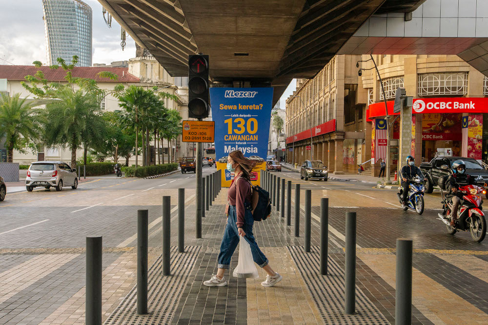 A woman wearing a face mask walks on a street, during the implementation of the movement control order (MCO 2.0) in Kuala Lumpur February 2, 2021. u00e2u20acu201d Picture by Firdaus Latif