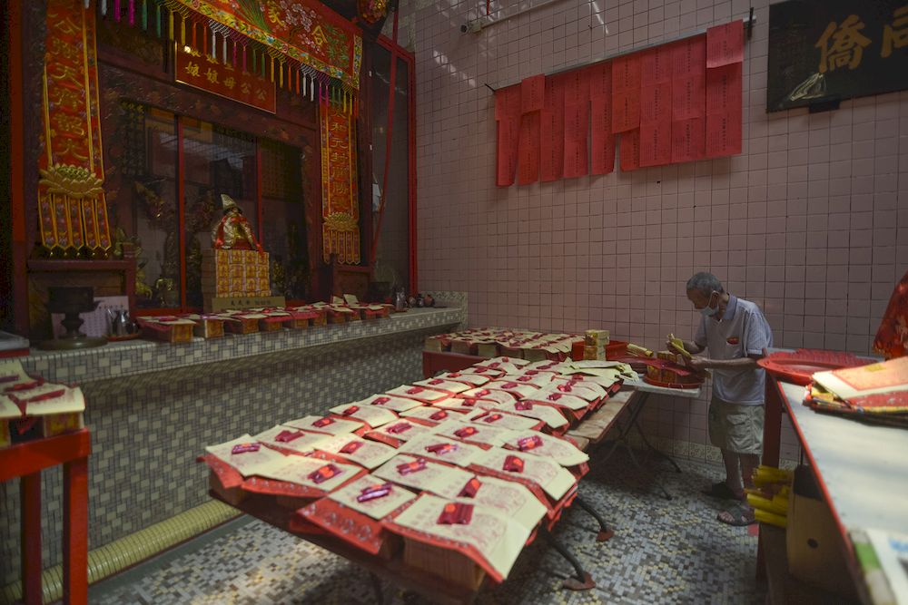 To help move visitors along, Sin Size Si Ya Taoist temple staff assist visitors with prayer requests. This is part of the Taoist temple's own initiative to minimise visitors inside the temple. — Picture by Miera Zulyana