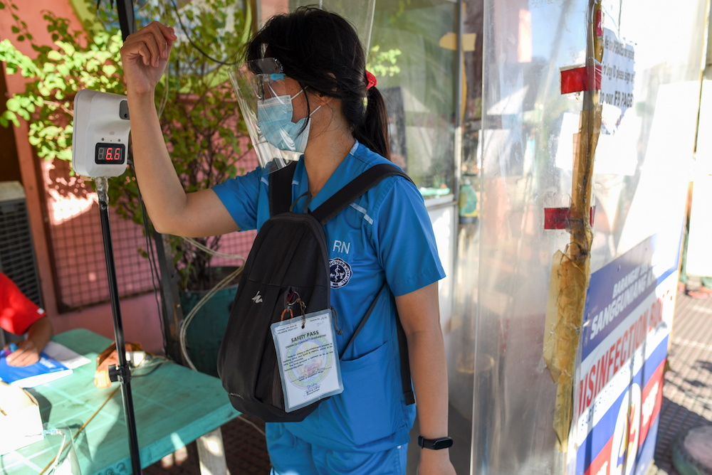 A woman wearing a face mask and a face shield as protection against the coronavirus disease checks her temperature at a community quarantine checkpoint, in Pasay, Metro Manila, Philippines, February 25, 2021. u00e2u20acu201d Picture courtesy of Reutersnnn