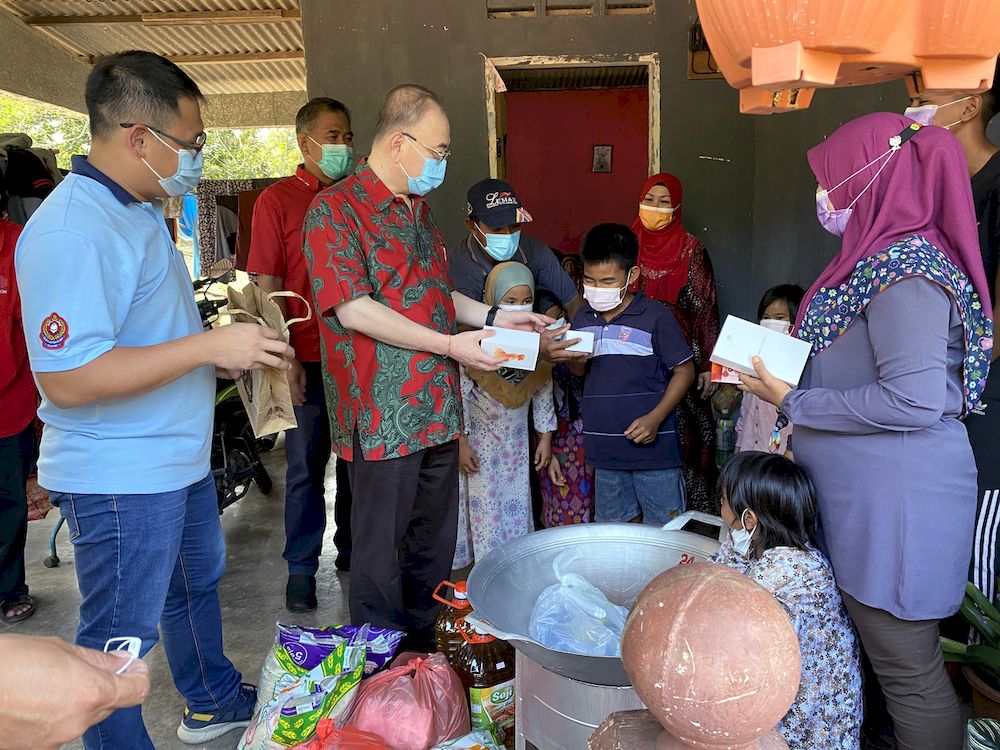 Ayer Hitam MP Datuk Dr Wee Ka Siong (third left) handing over two smartphones to the children of a single mother, Umi Naza Osman (right) to facilitate Home Teaching and Learning (PdPR), in Kampung Rahmat, Batu Pahat. u00e2u20acu201d Bernama pic