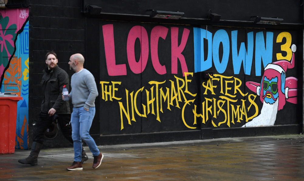 Pedestrians walk past graffiti reading u00e2u20acu02dcLockdown 3: The Nightmare after Christmasu00e2u20acu2122 painted on a boarded up restaurant in Manchester, England, February 15, 2021. u00e2u20acu201d Reuters picnn